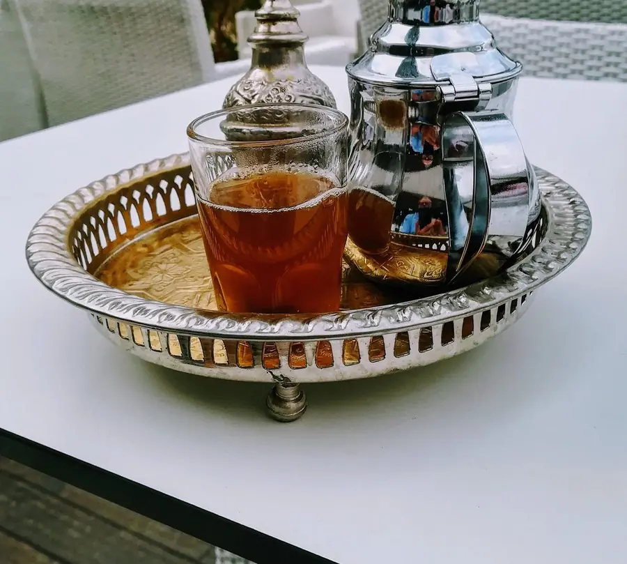 Mint tea glass and silver teapot on a traditional tray
